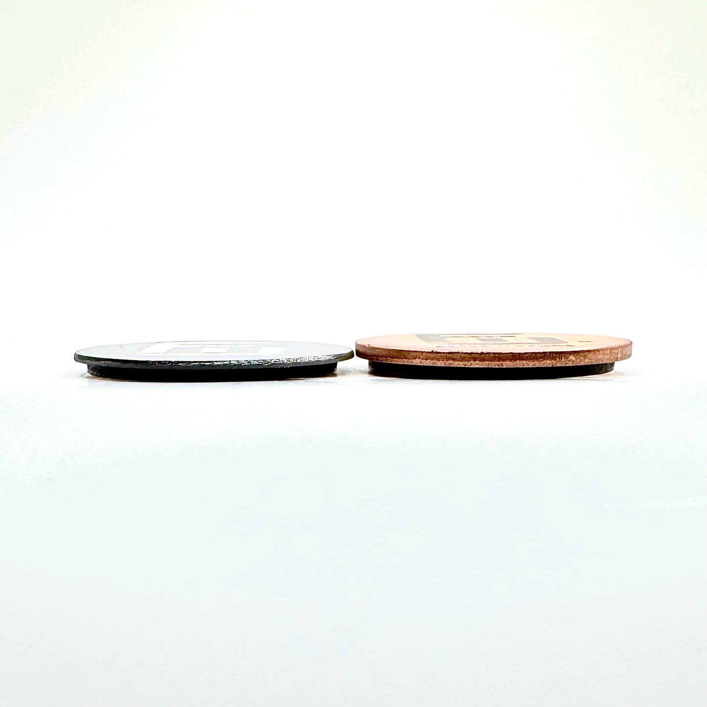 a 9g Tungsten flick weight next to a 9g copper flick weight to deomonstrate the size and thickness difference of metal density.