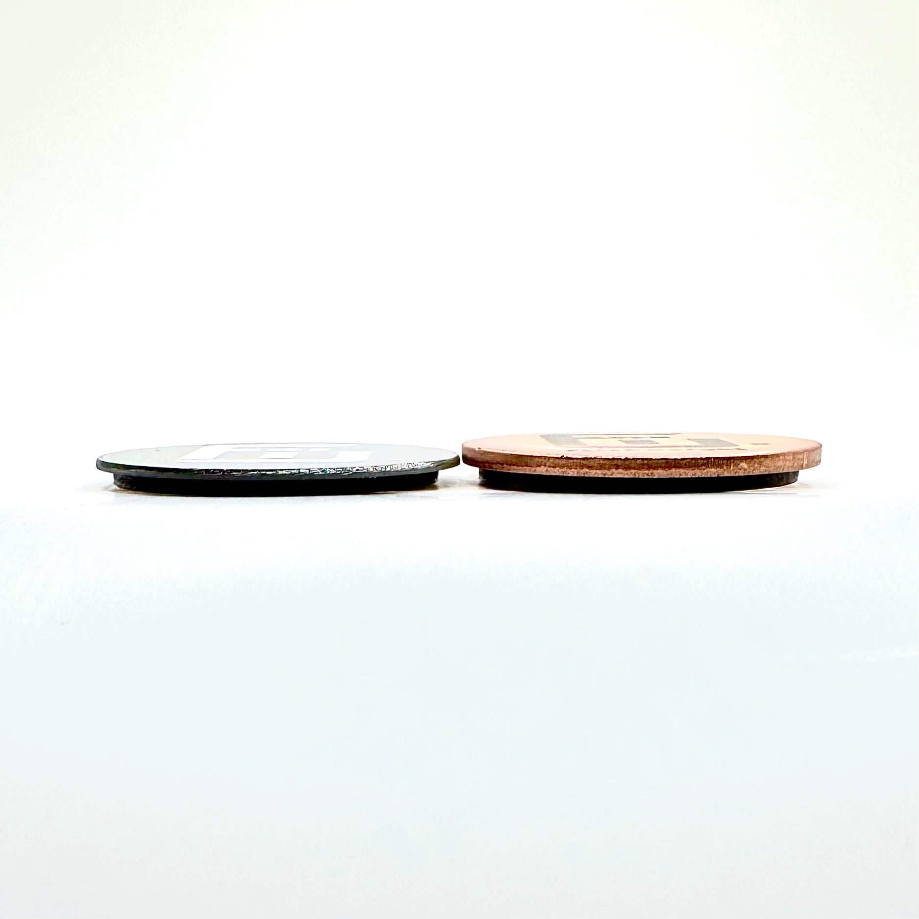a 9g Tungsten flick weight next to a 9g copper flick weight to deomonstrate the size and thickness difference of metal density.